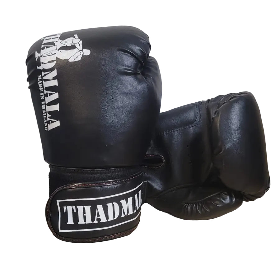 Black boxing gloves with 'THADMA' branding on a wooden surface.