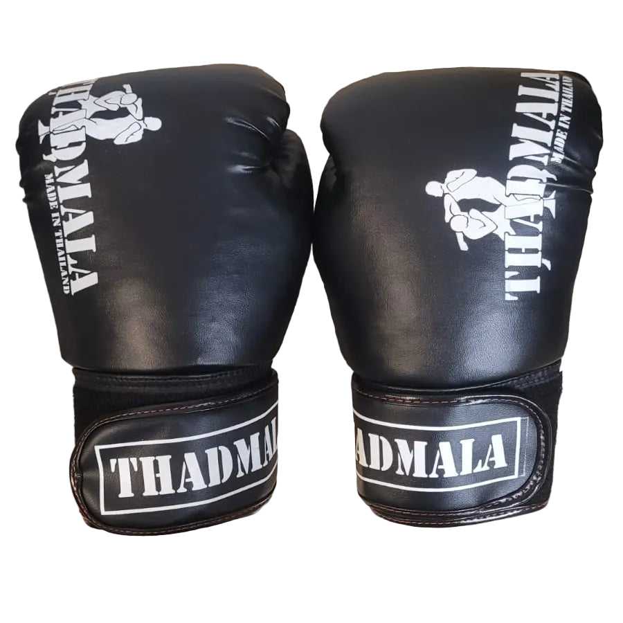 Pair of black boxing gloves with white text on a wooden surface, with a person's feet visible in the background.
