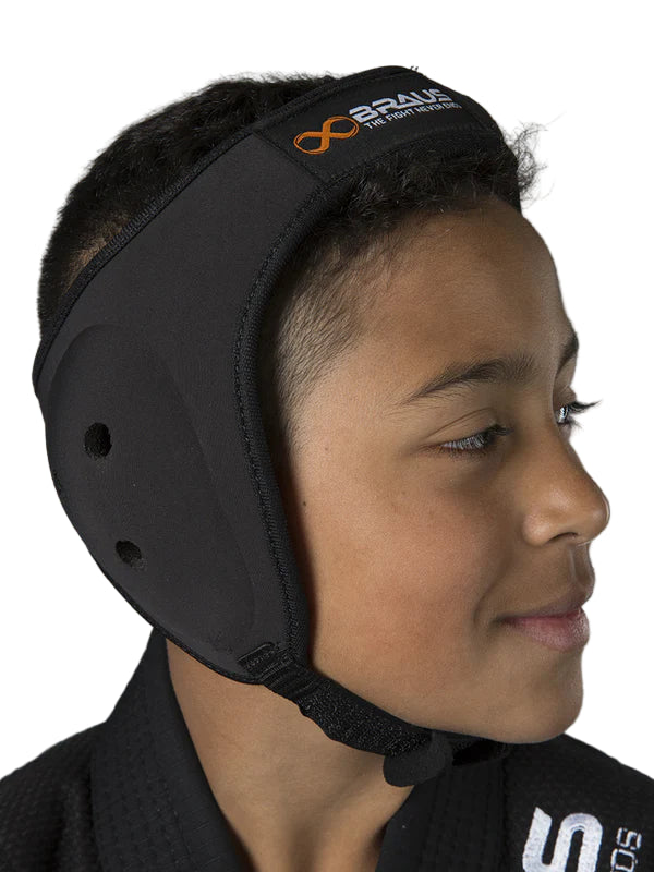 Child wearing a black headguard with a brand logo on a gray background
