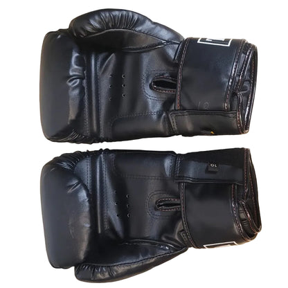Pair of black boxing gloves on a wooden surface with a person's feet in the background.